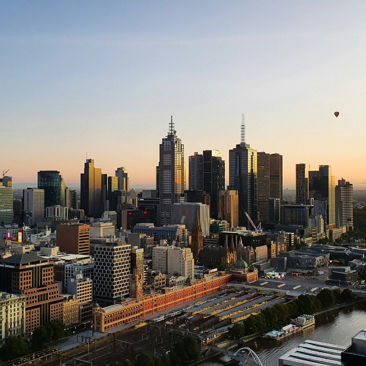 Melbourne aerial shot with view of Finders Street Station and Yarra River at sunset with hot air balloons